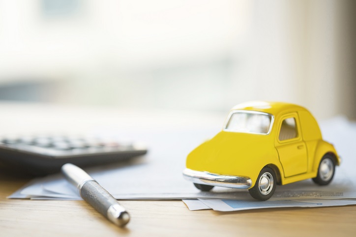 dokumenty ubezpieczeniowe i miniatura żółtego samochodu
